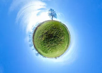 Little planet - spherical view of green fields with trees and blue sky